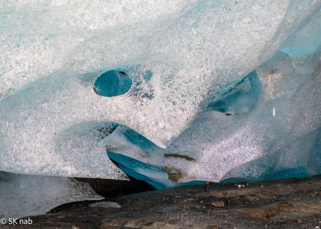 "Gesicht" in schimmerndem, weißem Gletschereis und blauem Hintergrund