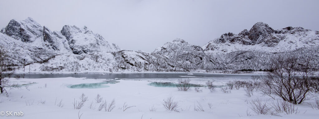 Verschneite Berggipfel und zugefrorener Fjord it grünem Eis - Vesterålen